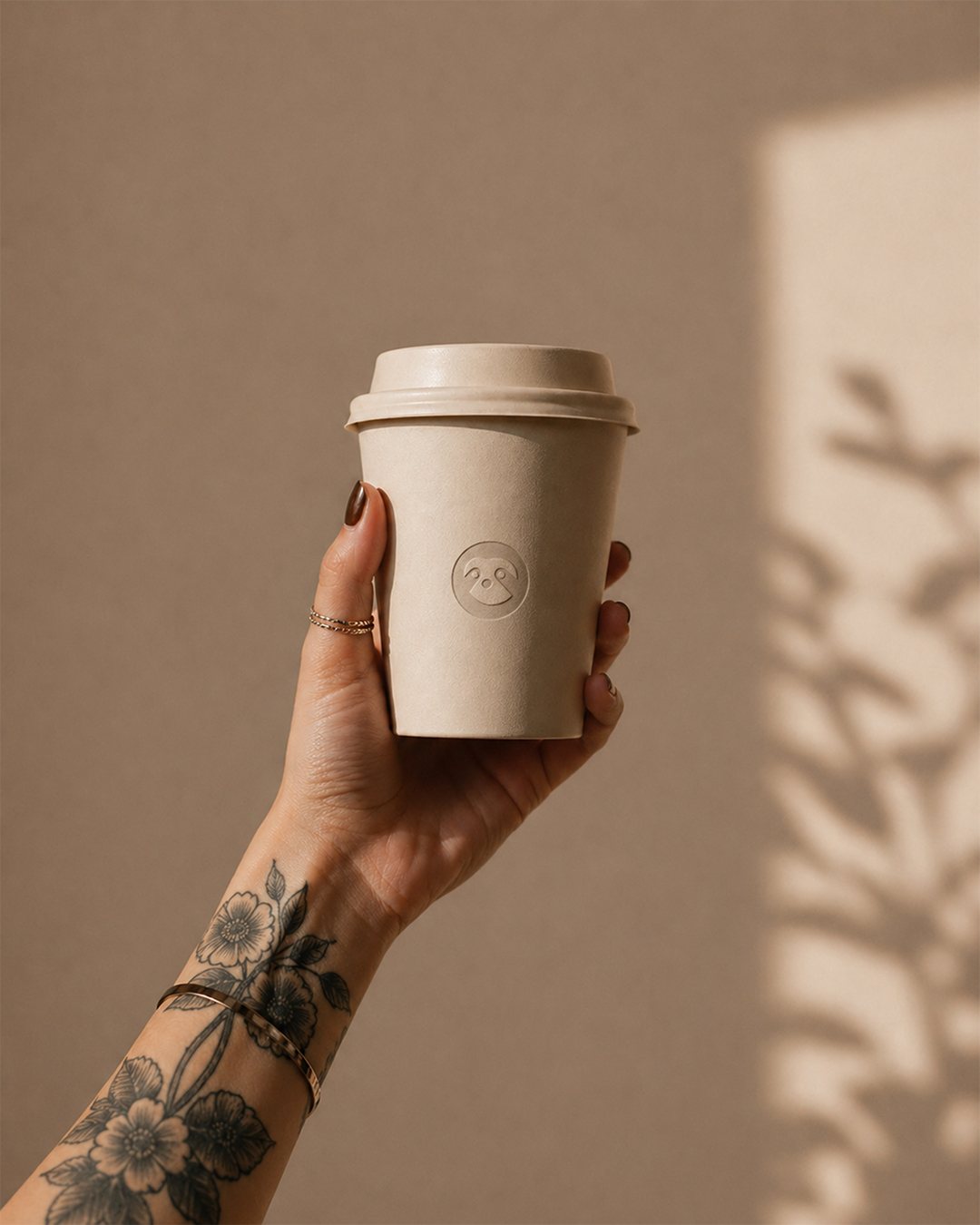 Hand holding a LENTO takeaway coffee cup with the sloth mark