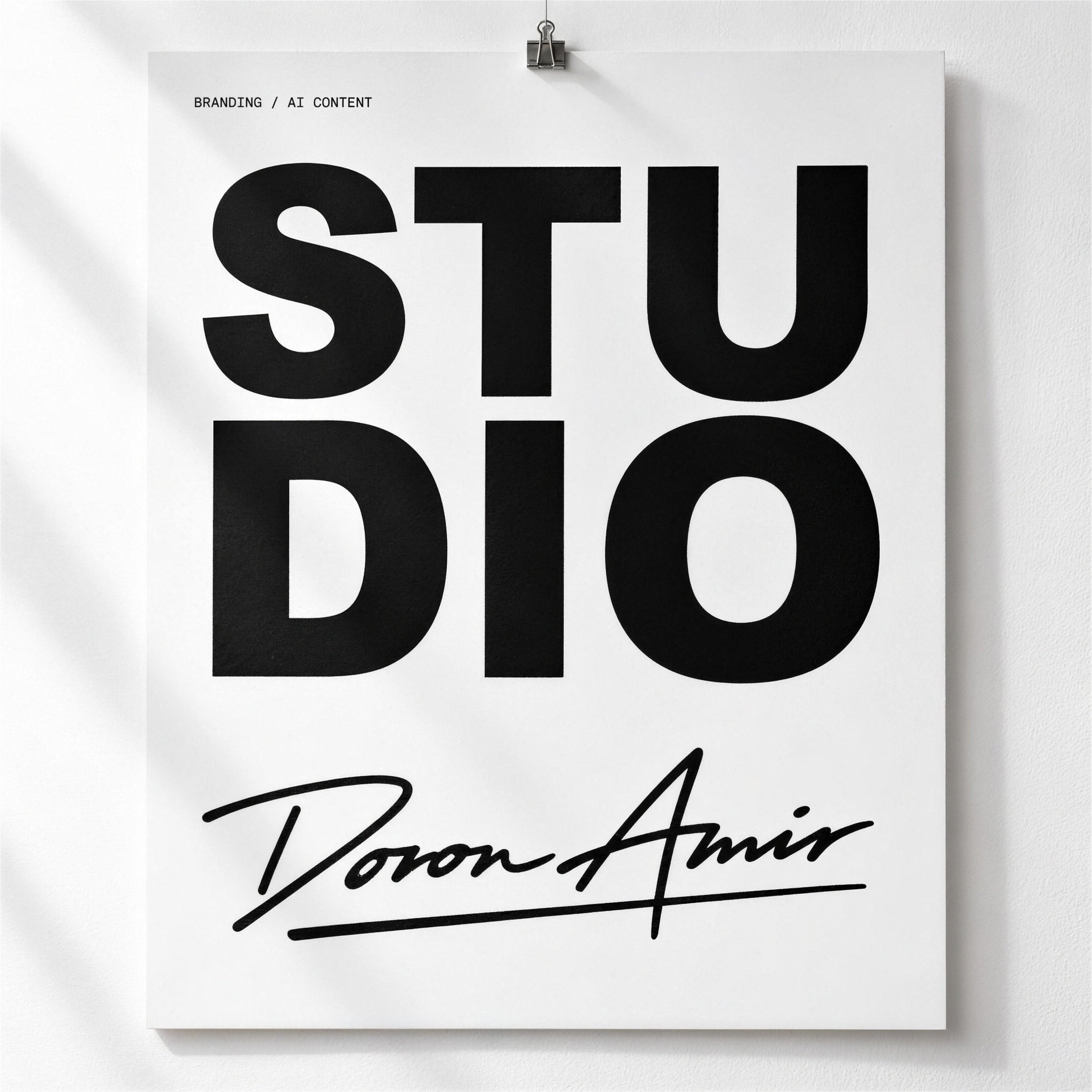 STUDIO poster with the Doron Amir signature, clipped to a white wall