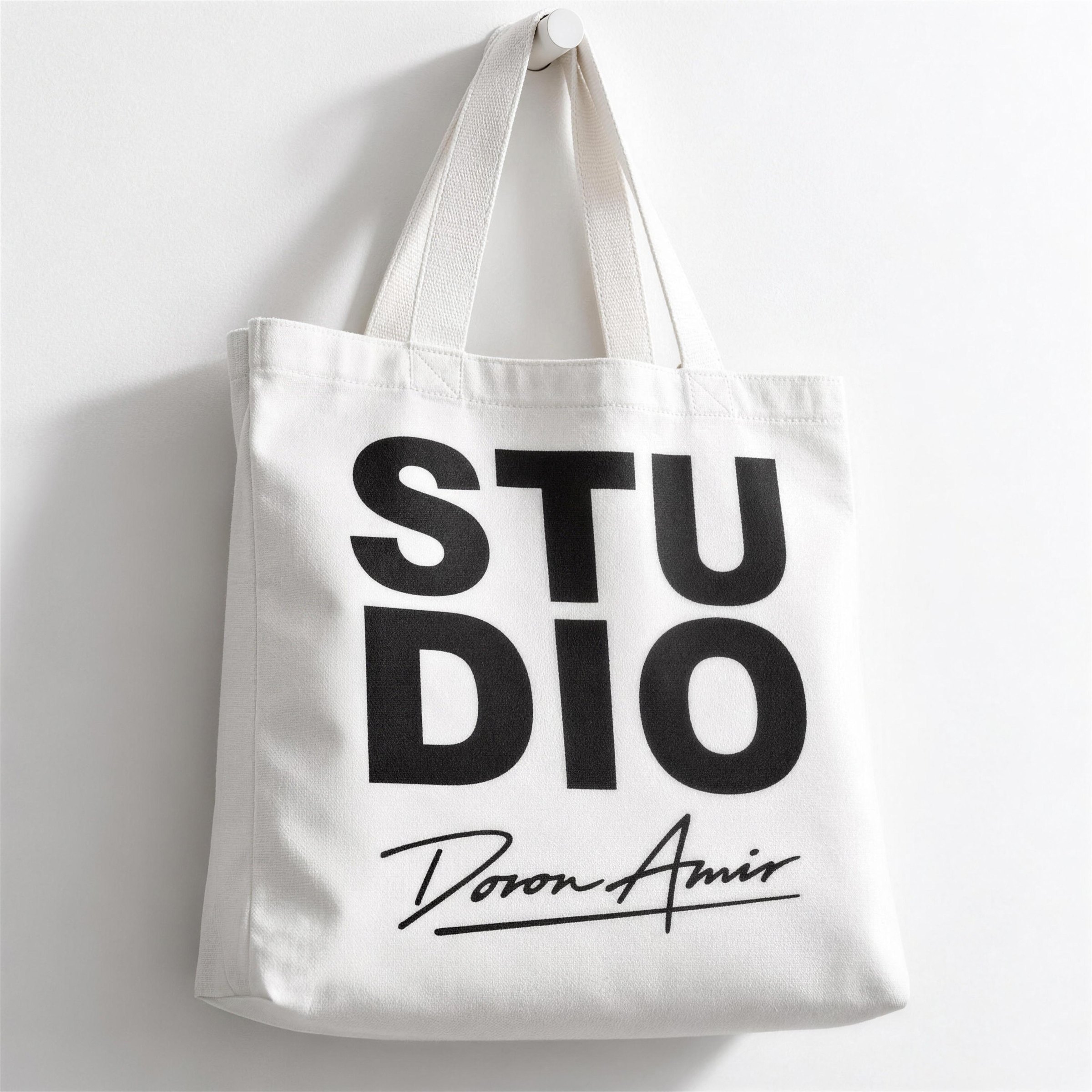White tote bag printed with STUDIO and the Doron Amir signature