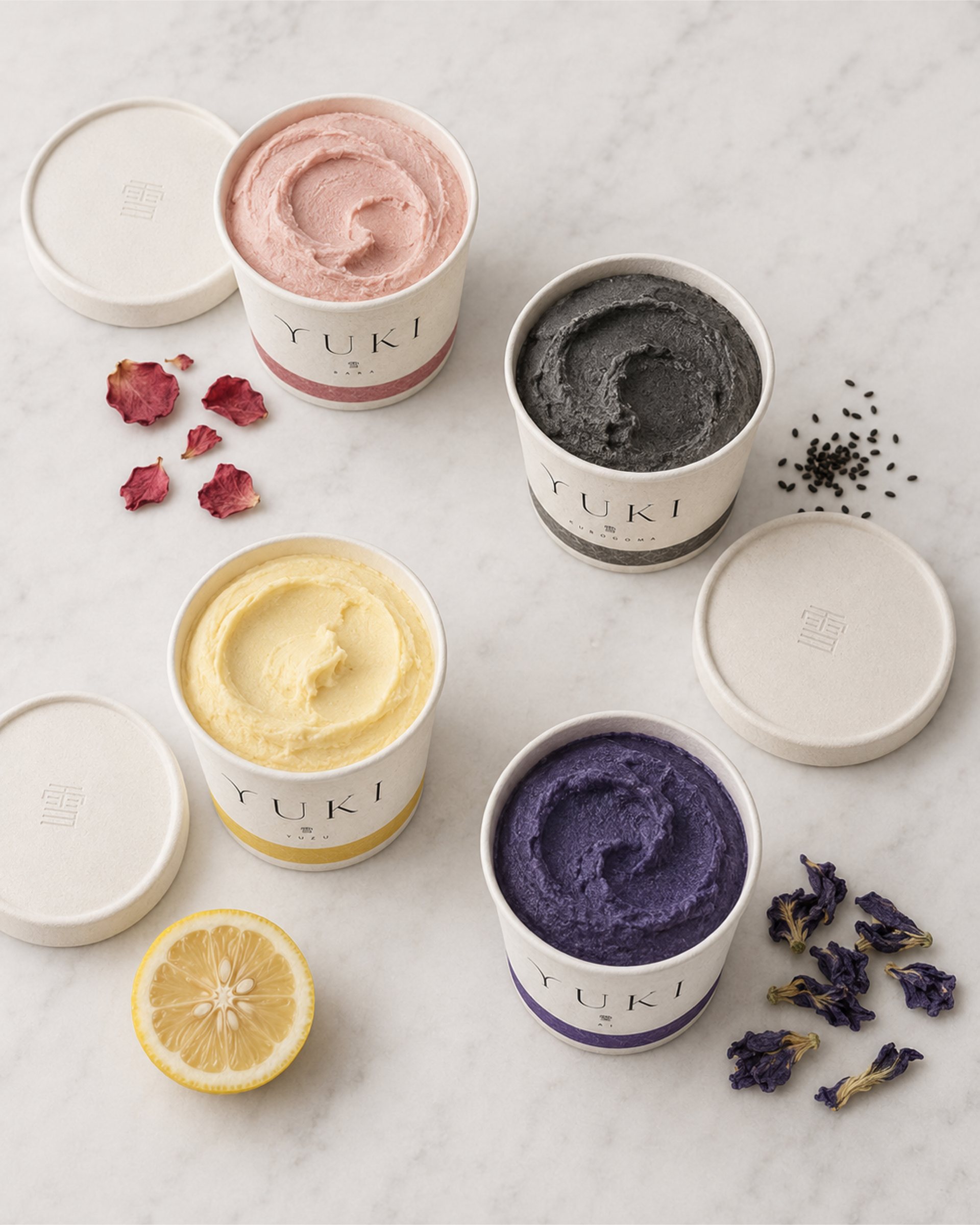 Open YUKI tubs in pink, black, lemon and purple flavours on marble